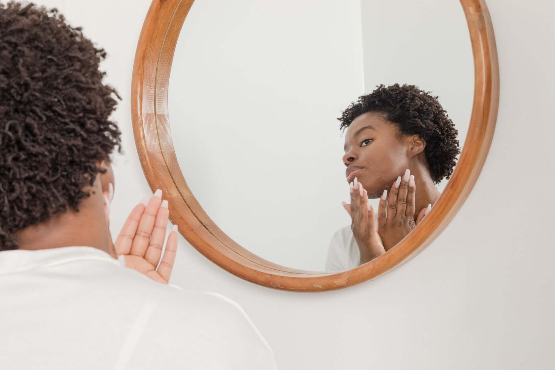 Femme devant un miroir se touchant le visage
