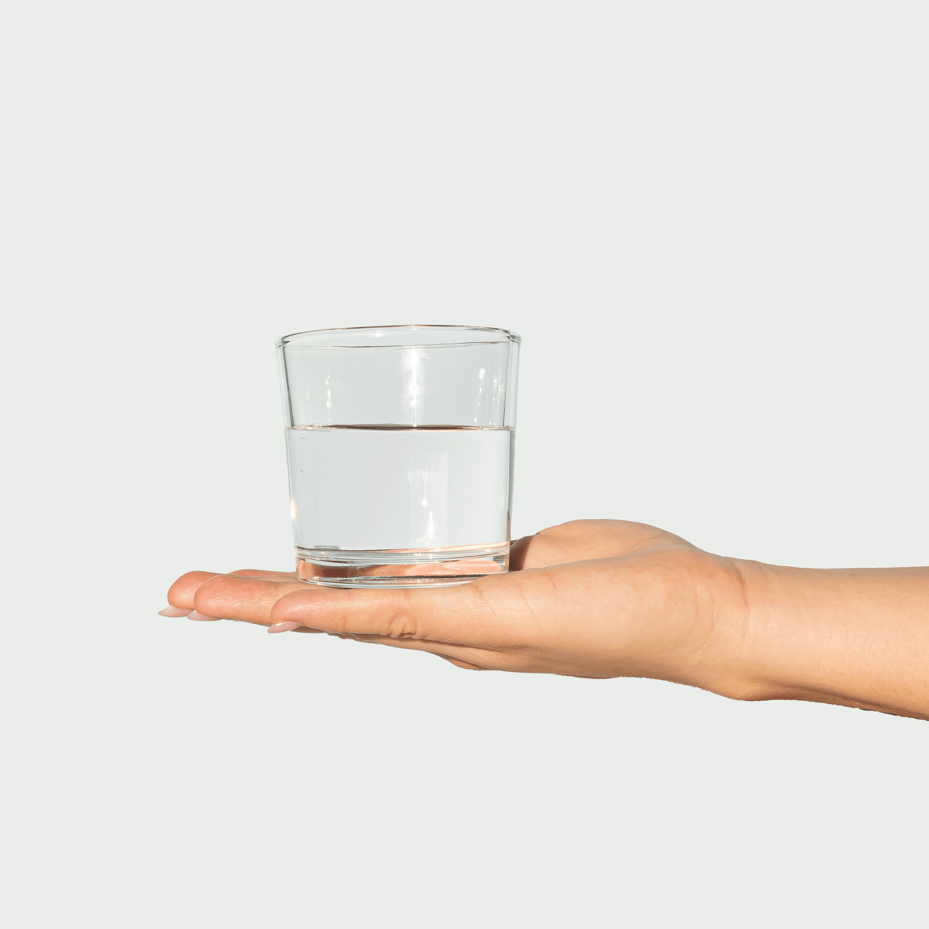 Main d'une femme qui tient un verre d'eau